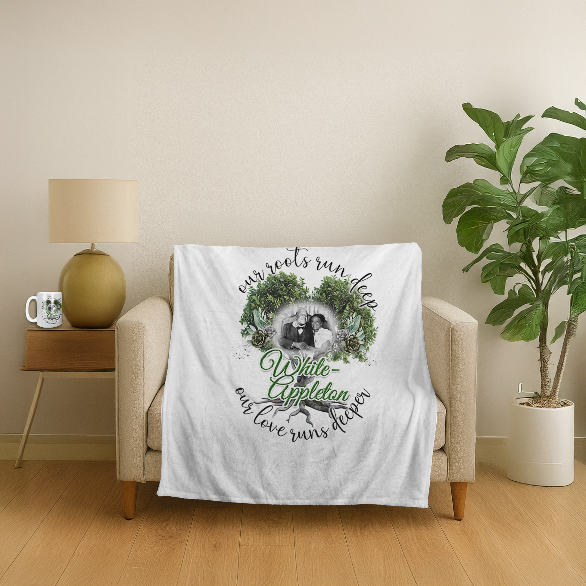 "White fleece blanket draped over a beige armchair, featuring a custom design with greenery wreath, family photo, and the text 'Our roots run deep, White-Appleton, our love runs deeper.' A matching mug with similar artwork sits on the side table in a cozy living room setting."
